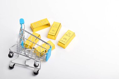 Alışveriş arabasındaki altın külçeleri beyaz arka planda izole edilmiş ve fotokopi alanı var. Üst görünüm