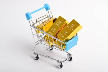 Beyaz arkaplanda izole edilmiş alışveriş arabasındaki altın külçeler