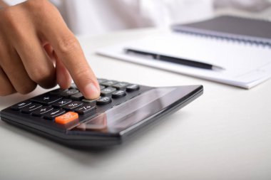 Ev finansmanını hesaplamak ve not yazmak için hesap makinesini kullanan yakın plan iş adamları, masa başında muhasebe, bütçe yönetimi. Finans, bütçe ve vergi hesaplamaları, aylık giderler