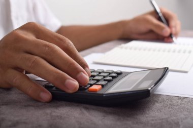 Ev finansmanını hesaplamak ve not yazmak için hesap makinesini kullanan yakın plan iş adamları, masa başında muhasebe, bütçe yönetimi. Finans, bütçe ve vergi hesaplamaları, aylık giderler