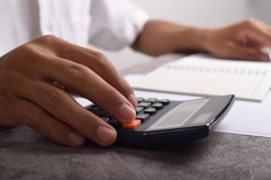 Ev finansmanını hesaplamak ve not yazmak için hesap makinesini kullanan yakın plan iş adamları, masa başında muhasebe, bütçe yönetimi. Finans, bütçe ve vergi hesaplamaları, aylık giderler