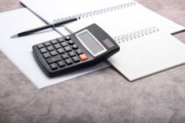 Muhasebe işyeri konsepti. Hesap makinesi, kalem, defter koyu gri arkaplan üzerinde izole edilmiş ve boş alan