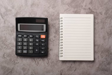 Koyu gri arkaplanda izole edilmiş hesap makinesi ve defter