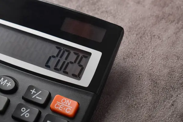 Gelecek yıl için bütçe konsepti. 2025 numaralı hesap makinesi koyu gri bir arkaplanda izole edilmiş.