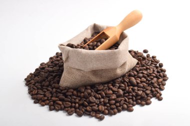 Beyaz arka planda izole edilmiş kavrulmuş kahve çekirdekleri ile çuval ve ahşap kepçe.