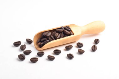 Kavrulmuş kahve çekirdekleri beyaz arka planda izole edilmiş ahşap kepçe.