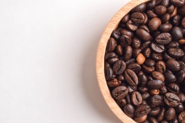 Beyaz arka planda izole edilmiş ahşap kasede kavrulmuş kahve çekirdeği. Üst Manzara. Düz yatıyordu. Polis alanı. Kapat.