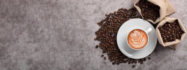 Koyu çimento arka planda bir fincan kahve ve fasulye.