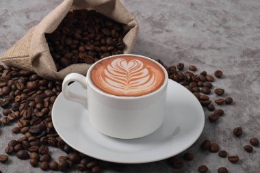 Sanat biçimli bir fincan kahve ve koyu çimento arkaplanda kahve çekirdekleri..