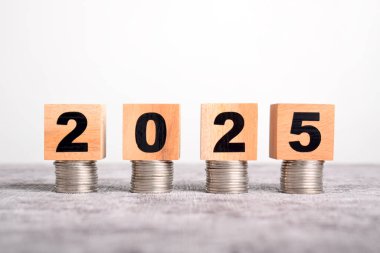 2025 yılına başlıyoruz. 2025 tahta küp blok ve para yığını. Teknoloji, vergi, finans, tasarruf kavramları
