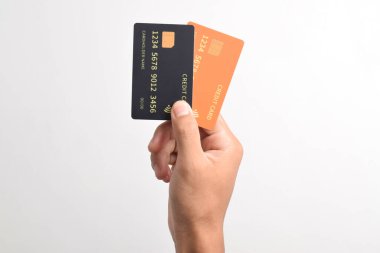 El, iki kredi kartı tutuyor. Siyah ve turuncu kredi kartları beyaz arka planda izole edilmiş.