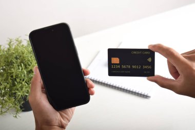 Akıllı telefon ve kredi kartı tutan erkek eller. Mobil ödeme, çevrimiçi alışveriş kavramı