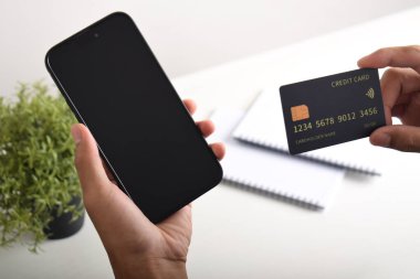 Akıllı telefon ve kredi kartı tutan erkek eller. Mobil ödeme, çevrimiçi alışveriş kavramı