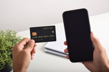 Akıllı telefon ve kredi kartı tutan erkek eller. Mobil ödeme, çevrimiçi alışveriş kavramı