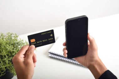 Akıllı telefon ve kredi kartı tutan erkek eller. Mobil ödeme, çevrimiçi alışveriş kavramı
