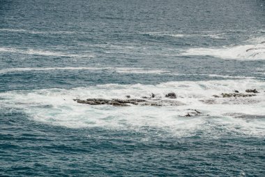 Koyu mavi suyun yüzeyi küçük dalgalar ve kayalarla dalgalanır..