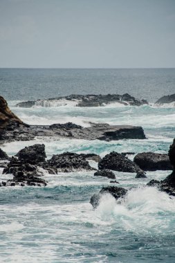 Okyanus dalgalarının kayalara çarptığı bir sahil.
