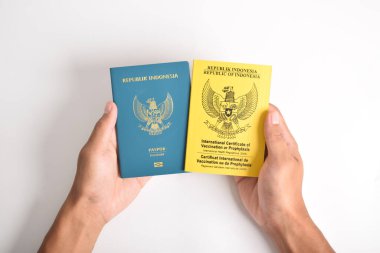 Pasaport ve Endonezya Aşı Sertifikası ya da Uluslararası Koruyucu Kitap 'ı tutan eller. Dünya Sağlık Örgütü 'nden uluslararası alanda tanınan sağlık pasaportu