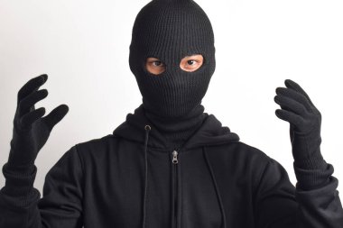 İki eli havada, beyaz arka planda izole edilmiş siyah ceket ve maske giyen bir hırsız. Hırsızlık ve suç kavramı