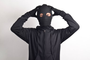 Siyah ceketli ve maskeli bir hırsız, beyaz arka planda soyutlanmış bir şekilde başını tutuyor. Hırsızlık ve suç kavramı