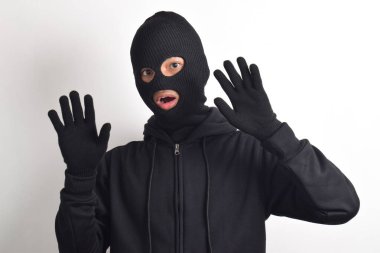 Siyah ceketli ve maskeli hırsız elleri havada yakalandı, beyaz arka planda izole edildi..