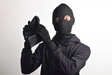 Siyah ceketli ve maskeli bir hırsız çalınan cüzdanını kontrol ediyor, beyaz arka planda izole edilmiş..