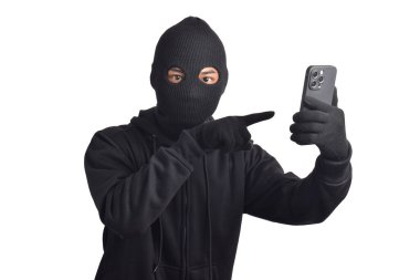 Siyah kapüşonlu ve maskeli gizemli adam akıllı telefondan hackleme aktivitesi yapıyor, akıllı telefonu işaret ediyor, beyaz arka planda izole edilmiş..