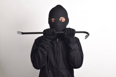 Siyah ceketli ve maskeli bir hırsız levye tutuyor, beyaz arka planda izole edilmiş..