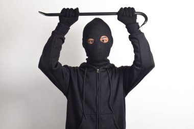 Siyah ceketli ve maskeli bir hırsız levye tutuyor, beyaz arka planda izole edilmiş..