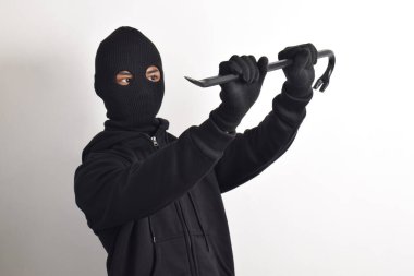 Siyah ceketli ve maskeli bir hırsız elinde korku dolu bir levyeyle beyaz arka planda izole edilmiş..
