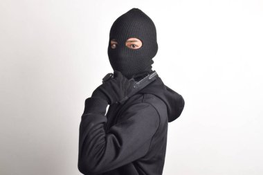 Siyah kapüşonlu ve maskeli silahlı gizemli bir adam, beyaz arka planda izole edilmiş..