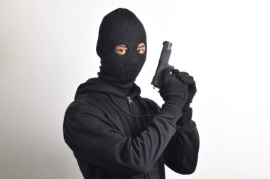 Siyah kapüşonlu ve maskeli silahlı gizemli bir adam, beyaz arka planda izole edilmiş..