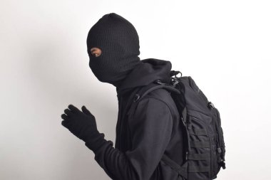 Siyah kapüşonlu, sırt çantalı ve maskeli gizemli bir adam kaçıyor, beyaz arka planda izole edilmiş. Soygun ve Hırsızlık Konsepti