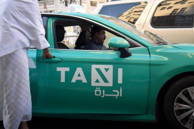 Makkah, Suudi Arabistan - 8 Mart 2025: Suudi Arabistan 'da Hac veya umrah yolcularını arayan yeşil sedan model bir arabayla taksi