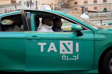 Makkah, Suudi Arabistan - 8 Mart 2025: Suudi Arabistan 'da Hac veya umrah yolcularını arayan yeşil sedan model bir arabayla taksi