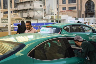 Makkah, Suudi Arabistan - 8 Mart 2025: Suudi Arabistan 'da Hac veya umrah yolcularını arayan yeşil sedan model bir arabayla taksi