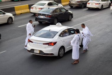Makkah, Suudi Arabistan - 8 Mart 2025: Suudi Arabistan 'da Hac veya umrah yolcularını arayan beyaz sedan model bir arabayla taksi