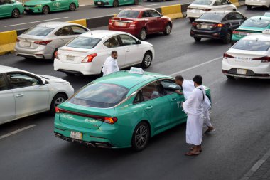 Makkah, Suudi Arabistan - 8 Mart 2025: Suudi Arabistan 'da Hac veya umrah yolcularını arayan yeşil sedan model bir arabayla taksi