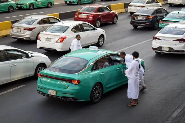 Makkah, Suudi Arabistan - 8 Mart 2025: Suudi Arabistan 'da Hac veya umrah yolcularını arayan yeşil sedan model bir arabayla taksi
