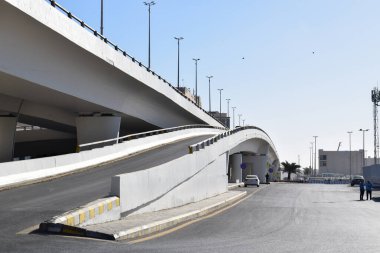 Madinah, Suudi Arabistan - 2 Mart 2025: Açık mavi gökyüzü altında beton yapıya sahip modern kentsel üstgeçit. Kavisli rampalar. Şehir altyapısı ve ulaşım kavramı.