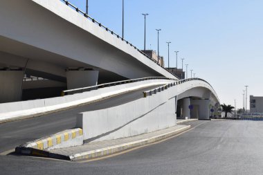 Açık mavi gökyüzünün altında beton yapısı olan modern kentsel üstgeçit. Kavisli rampalar. Şehir altyapısı ve ulaşım kavramı.