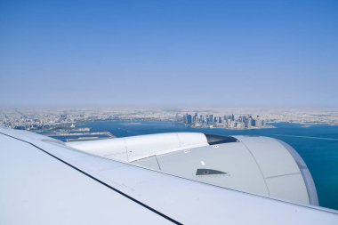 Gökyüzü açık mavi gökyüzü ve modern Katar şehir manzaralı Doha ufuk çizgisi ve uçak penceresinden kıyı şeridi.