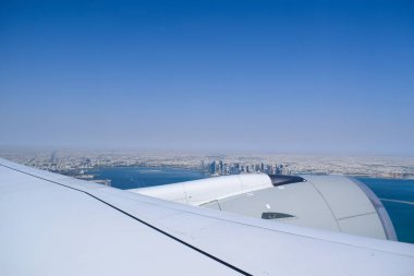 Gökyüzü açık mavi gökyüzü ve modern Katar şehir manzaralı Doha ufuk çizgisi ve uçak penceresinden kıyı şeridi.