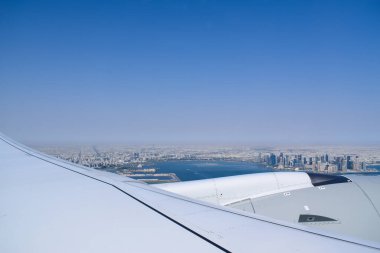 Gökyüzü açık mavi gökyüzü ve modern Katar şehir manzaralı Doha ufuk çizgisi ve uçak penceresinden kıyı şeridi.