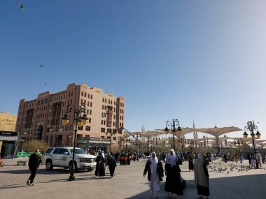 Al-Madinah al-Munawwarah, Suudi Arabistan - 1 Mart 2025: Açık mavi gökyüzü altında açık şemsiyeler ve minarelerle Medine 'deki Peygamber Camii.