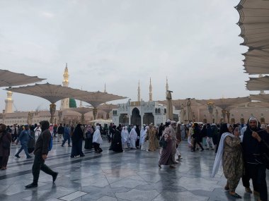 Al-Madinah al-Munawwarah, Suudi Arabistan - 27 Şubat 2025: Medine 'de Peygamberin Camii açık şemsiyeler ve minarelerle bulutlu bir gökyüzü altında, İslami mimariyi gözler önüne seren.