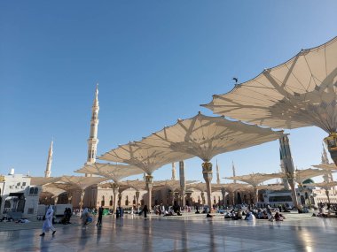 Al-Madinah al-Munawwarah, Suudi Arabistan - 1 Mart 2025: Açık mavi gökyüzü altında açık şemsiyeler ve minarelerle Medine 'deki Peygamber Camii.