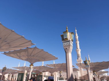 Al-Madinah al-Munawwarah, Suudi Arabistan - 1 Mart 2025: Açık mavi gökyüzü altında açık şemsiyeler ve minarelerle Medine 'deki Peygamber Camii.