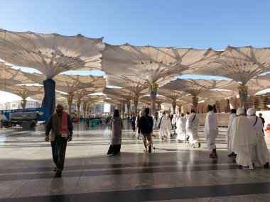 Al-Madinah al-Munawwarah, Suudi Arabistan - 1 Mart 2025: Açık mavi gökyüzü altında açık şemsiyeler ve minarelerle Medine 'deki Peygamber Camii.