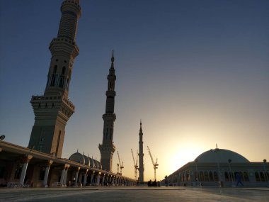 Madinah, Suudi Arabistan - 1 Mart 2025: Medine 'de peygamberin mescitinin çatısı ve yükselen minareleri gün doğumunda